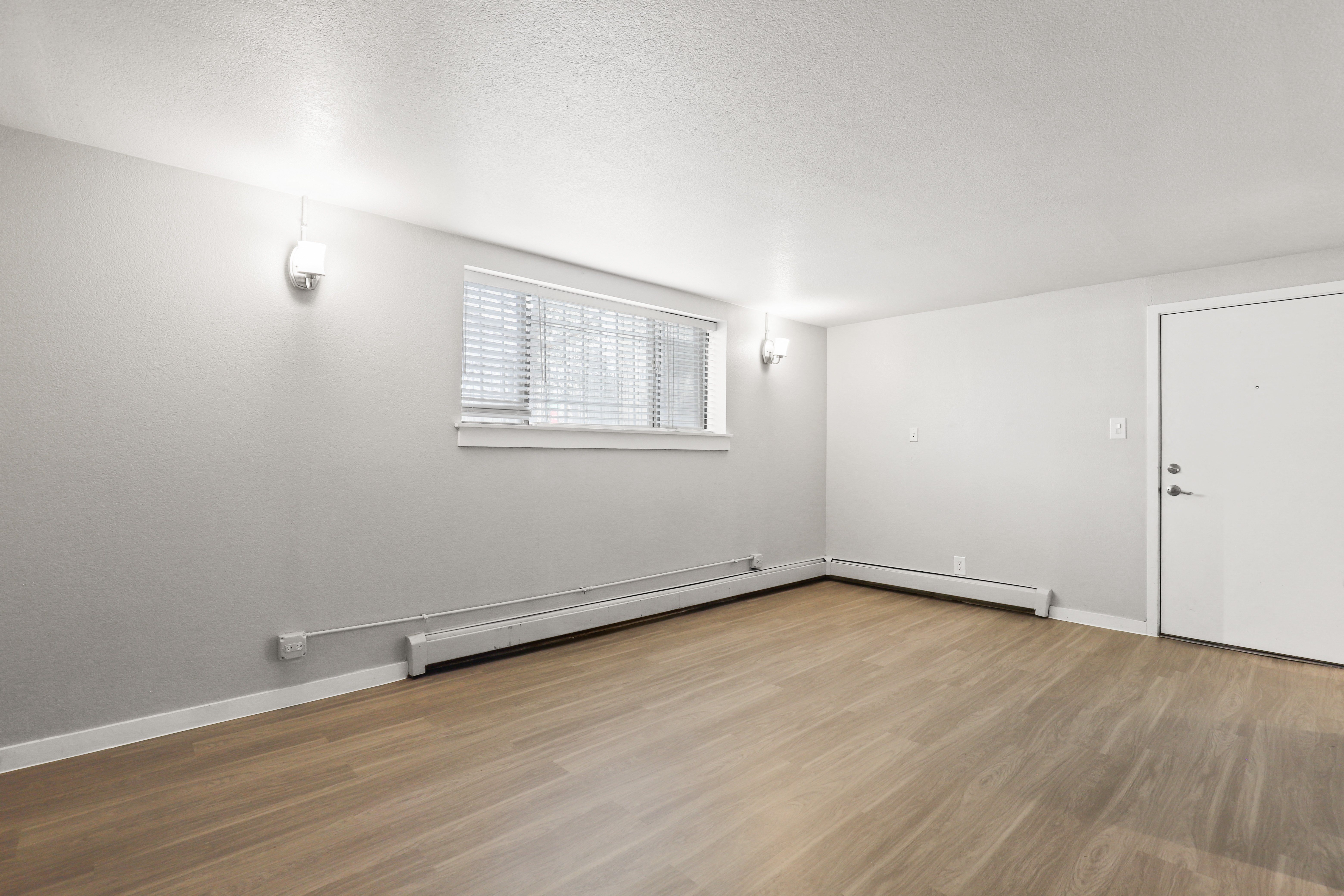 the living room of an empty apartment with wood flooring and a window